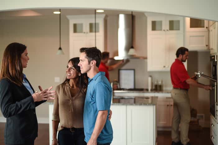 Dallas real estate agent and couple talking with home inspectors in background
